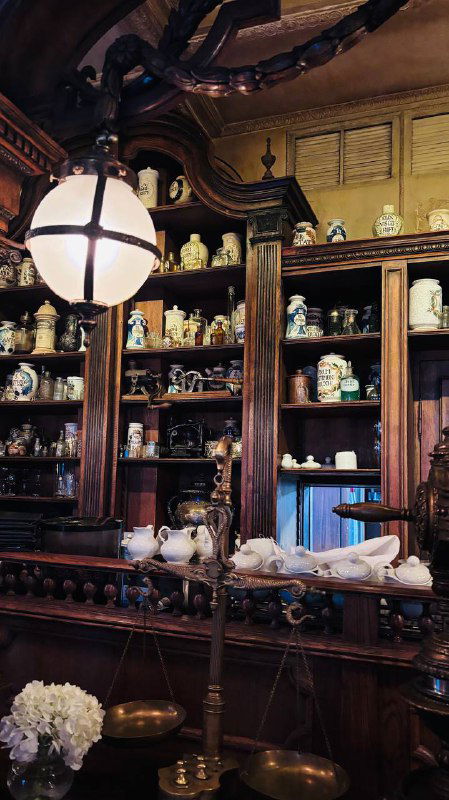 Витрина и декоративные полки с фарфором и домашними предметами внутри ресторана «Пушкинъ», детали декора и антикварные элементы снимок вертикальный.