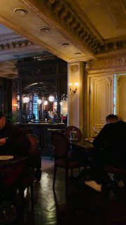 Общий вид зала ресторана с гостями, столами и зеркалами — тёплое освещение и классические мебель и люстры, атмосфера вечернего обеда.