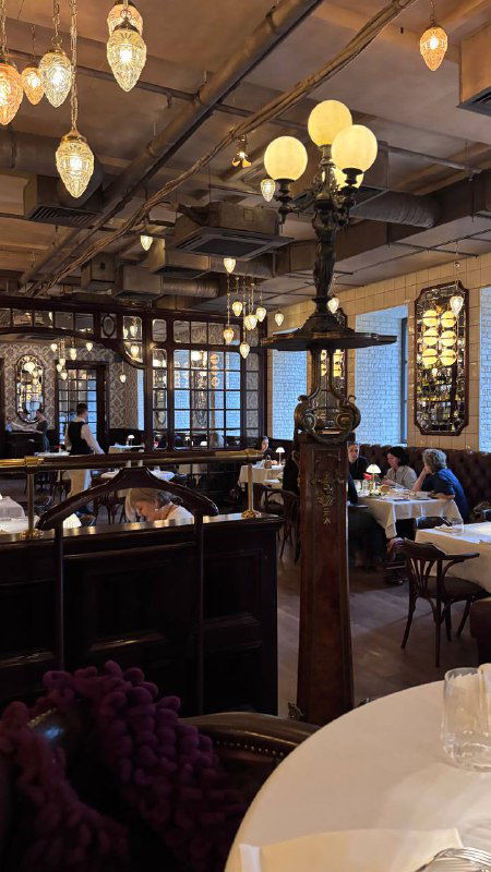 Интерьер одного из залов Шануар: круглые столы, кресла, старинные люстры и декоративные элементы — роскошная вечерняя атмосфера заведения.