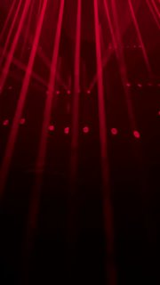 Красные лучи и вертикальные световые столбы создают интенсивную атмосферу лазерного перформанса внутри экспозиции, видно элементы сценографии.