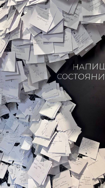 Стена, усыпанная бумажными записками и карточками — посетители оставляют послания и состояния в рамках интерактивной части выставки.