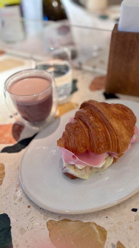 Завтрак в Margarita Bistro: воздушный круассан с начинкой и небольшой стаканчик напитка на столе — снимок блюда с акцентом на десерт/завтрак.