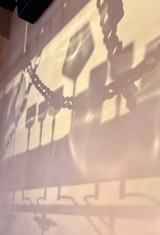 Тень от подвешенных бокалов и элементов декора на стене ресторана — художественный кадр, придающий месту атмосферу вечера.