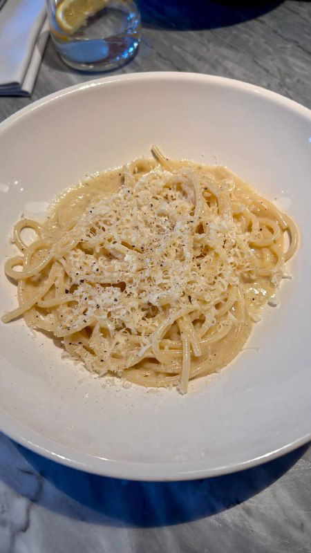 Тарелка со спагетти качо э пепе: паста с кремовым сырным соусом и перцем, сервировка в белой глубокой тарелке.