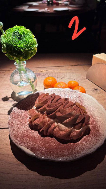 Тирамису с воздушным кремом на тарелке, рядом декоративный цветок и сыр, снимок из обзора ресторанных десертов в Москве.