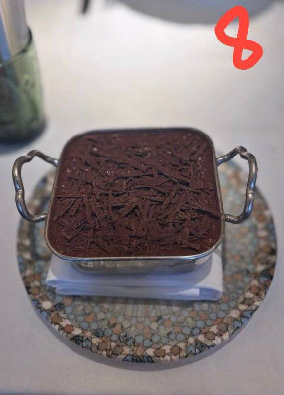 Большая квадратная форма тирамису с тёртым шоколадом сверху, сервирована в металлическом контейнере, снимок из обзора.