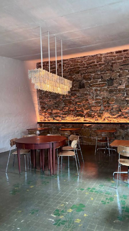 Общий вид зала с деревянными потолочными балками, круглым столом и стульями, приглушённая подсветка и свободное пространство в зале.