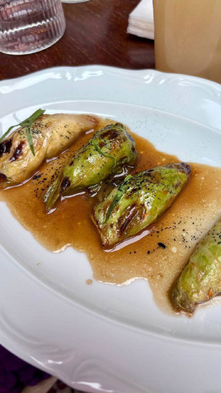 Тарелка с фаршированными патисонами в подливе — деталь меню ресторана, крупный план блюда с соусом и прожаркой.