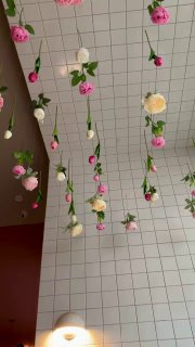 Декоративные висящие цветы под плиточным потолком кафе, вид на гирлянды роз и белых бутонов в интерьере Balik.