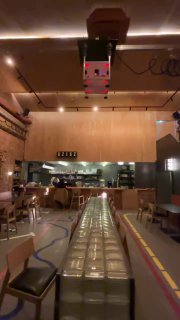 Внутренний вид бара «Кирпичик» в Ростове: длинный стол из стеклоблоков в центре зала, индустриальная отделка потолка и тёплое освещение.