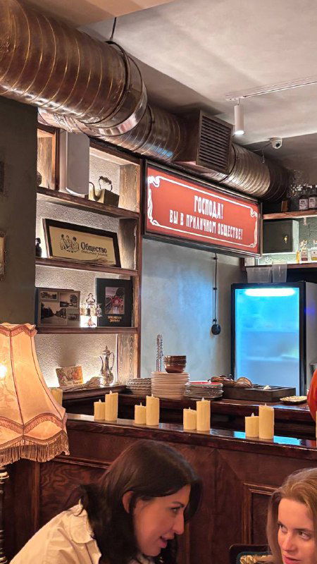 Интерьер с деревянными элементами, настольными лампами и декоративными буквами на полках — уютный ретро‑декор и детали бара.