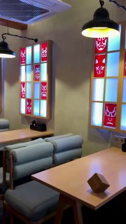 Уютные диваны и деревянные столы у окна, цветные витражи с масками и подвесные лампы в стиле идзакая.