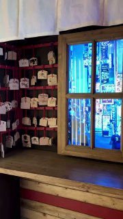 Небольшая алтарная зона или уголок с деревянными табличками-эмами и окном, через которое видно уличный неон.