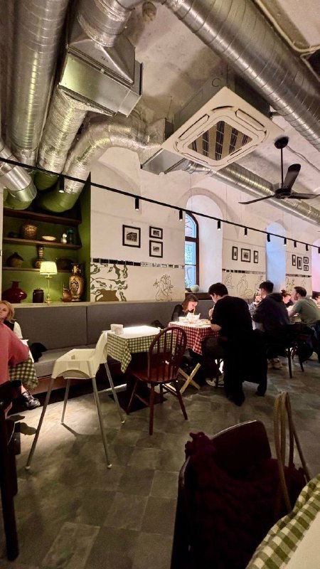 Интерьер Osteria by Mandy's: залы с клетчатыми скатертями, гости за столами и открытая система вентиляции под потолком ресторана