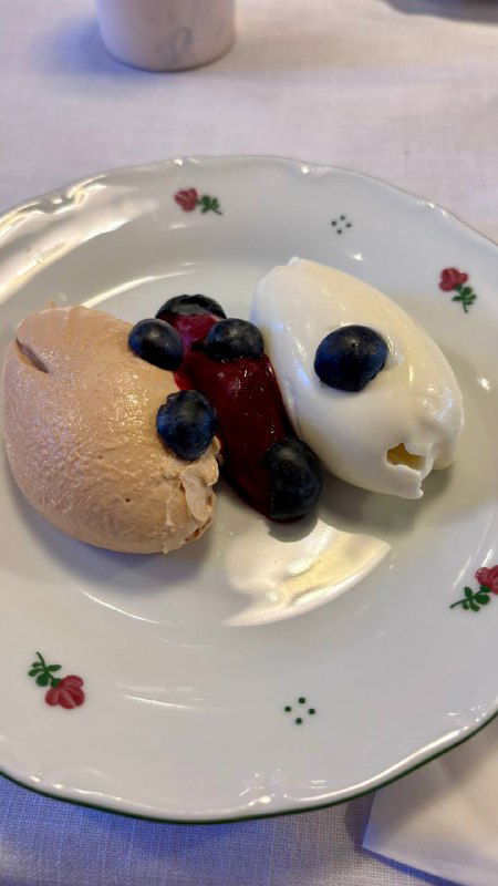 Десертный состав: взбитый топлёный творог рядом с шариком сорбета из чёрной смородины и ягодами, минималистичная подача на фарфоровой тарелке.