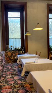 Интерьер ресторана Mamie: светлая зона с обеденными столами, настенные окна, лампы над столами и уютная атмосферная расстановка мебели.