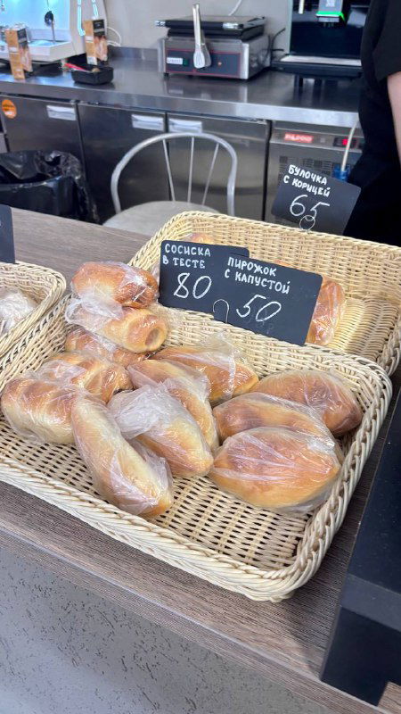 Пирожочки и выпечка на прилавке универской столовой: корзины с булочками и ценники, столовая атмосфера и ностальгический штрих посещения кампуса.