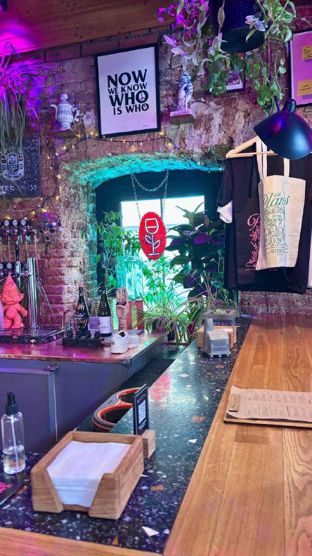 Барная стойка в Mission: инструменты бара, растения, подсветка и декоративные детали на фоне кирпичной стены и постеров.