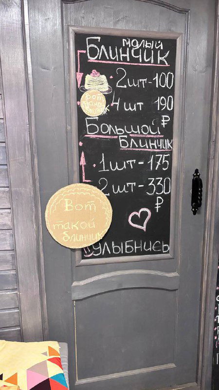 Дверь с меню на меловой доске: «малый блинчик 2шт» — фотография фасада или входа в маленькое блинное кафе в центре Москвы рядом с храмом.