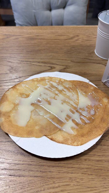 Тонкий блин с глазурью на белой тарелке, крупный план одной порции из маленького блинного заведения — аппетитный вид блюда.