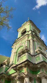 Боковой вид на колокольню с акцентом на текстуру стен и декоративные элементы, насыщенное синее небо и контрастная подсветка фасада в дневном свете.