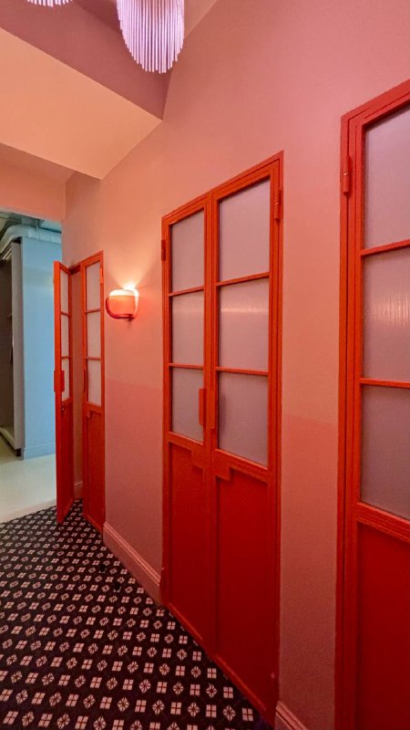 Коридор и двери в интерьере «Лолиты»: розовые и коралловые оттенки, декоративные панели и узорчатое ковровое покрытие ресторана.