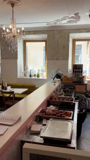 Буфет и стойка в интерьере кафе Публика: витрина с выпечкой и подносами с блюдами, столики и освещение на заднем плане.