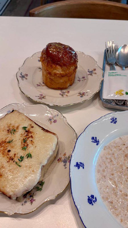 Тарелка с маленьким куличом в карамельной шапке, рядом крокмадам с крабом и овсяная каша — крупный план подачи завтрака в кафе.