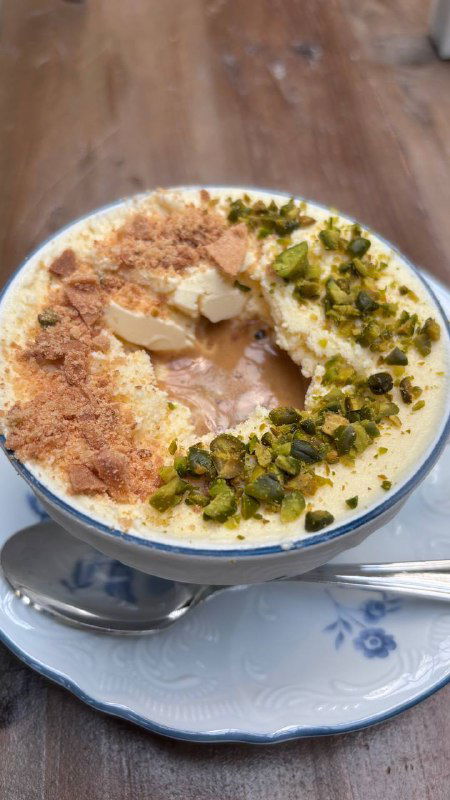 Порция аффогато «лимонный пирог» в чашке: сливочная основа, крошки, кусочки лимона и дроблёные фисташки, подача на блюдце в кафе.