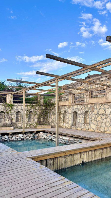 Каменная купальня и деревянные настилы в дизайнерской зоне на Кудыкиной горе — бассейн или источник в окружении стены.