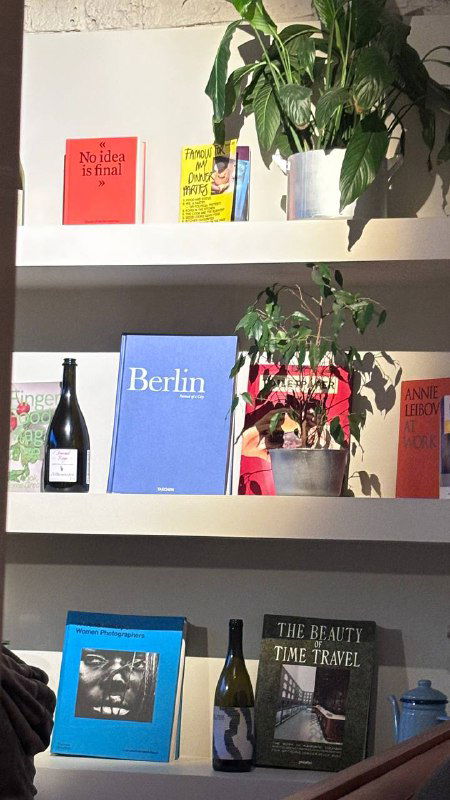 Полка с книгами, растениями и декоративными предметами внутри ресторана from Berlin, уютный уголок интерьера заведения.