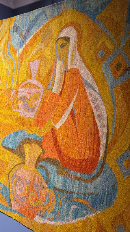 Фрагмент ковра с крупной фигуральной сценой: стилизованная персона на фоне мягких цветовых переходов, текстура нитяного плетения видна вблизи.