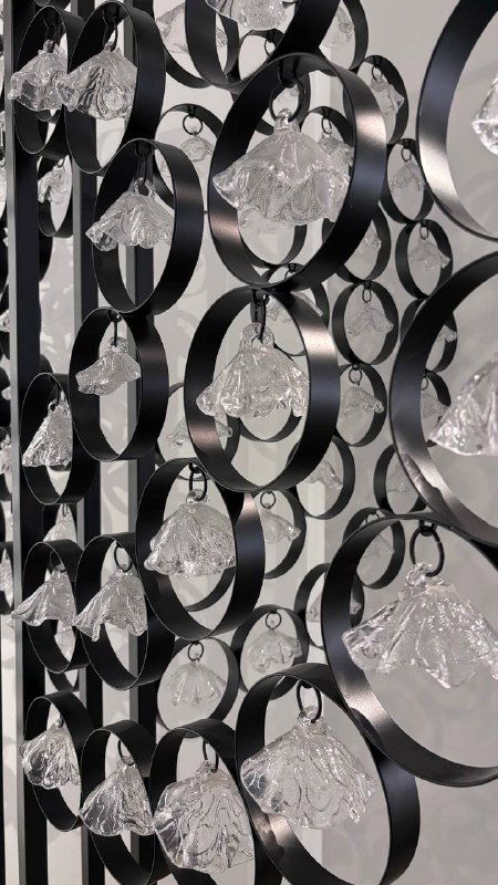 Чёрная металлическая конструкция с подвешенными прозрачными стеклянными элементами — близкий план декоративных стеклянных декоров в музее.
