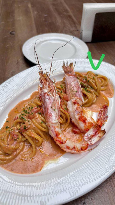 Тарелка пасты с крупными креветками, соусом и зеленью, сервировка в ресторане, на фото видна зелёная галочка — победитель финала.