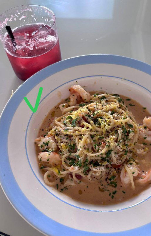 Паста в кремовом соусе с мелкими креветками и зеленью, тарелка на столе рядом с коктейлем, пометка галочкой — попала в подборку.