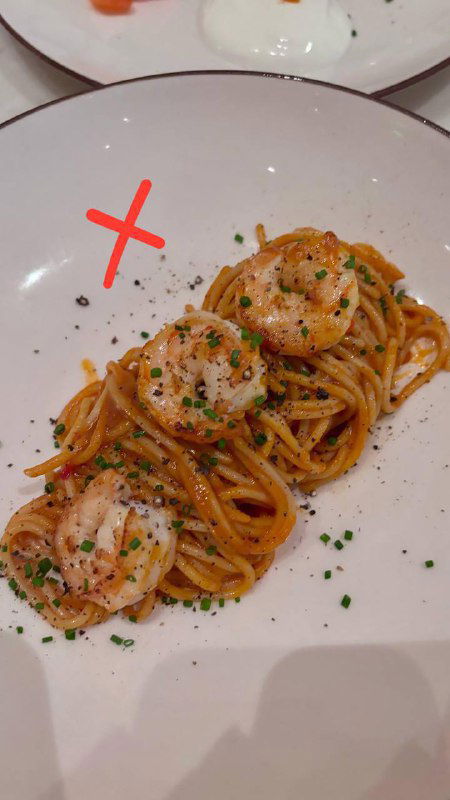 Небольшая порция пасты с креветками на белой тарелке, аккуратная подача, красный крест помечает блюдо как исключённое из подборки.