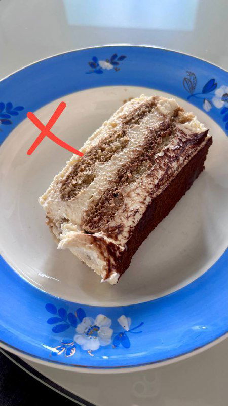 Порция тирамису на синей тарелке в домашней подаче; фотография помечена крестом, как непризнанный по вкусу вариант.