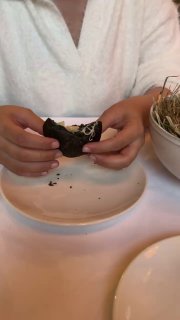 Гости разрывают чёрный пирожок, видно сырную тянущуюся начинку; интерьер и белая скатерть на столе — фото из обзора в Christian, Москва