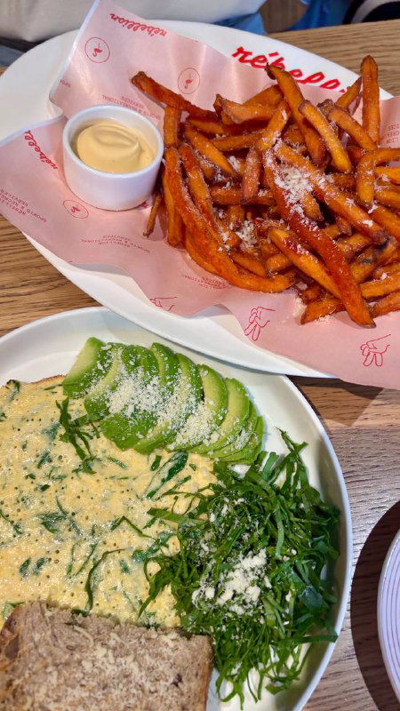 Тарелка с зелеными добавками и хлебцем на столе в кафе — вид блюд Rebellion при дневном свете; спокойная сервировка для легкого перекуса.