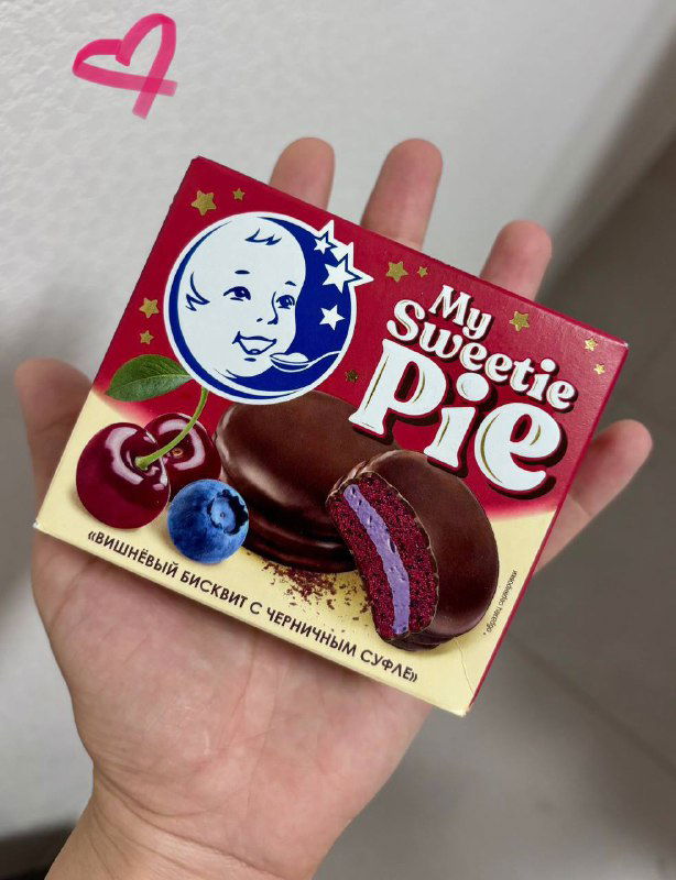 Коробочка с чокопаем My Sweetie Pie в руке: упаковка с иллюстрацией и вид сбоку на десерт черника-вишня, яркие цвета упаковки.