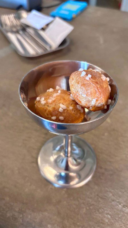 Маленькая серебряная рюмка с заварными булочками, посыпанными крупной солью, комплимент от кухни бистро Метеорит.