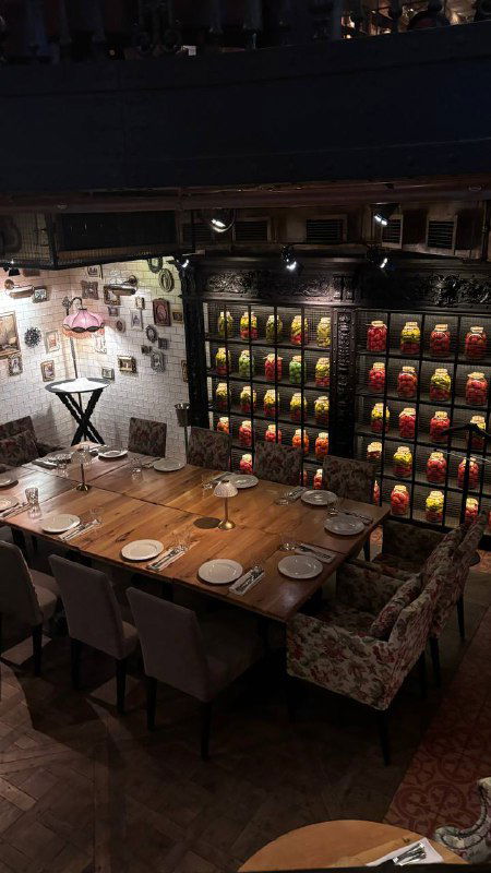 Большой сервированный стол для компании, декоративная настенная полка с предметами декора и уютная постановка для группового ужина.