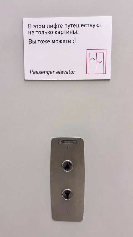 Табличка и панель лифта в музее с текстом о том, что в этом лифте путешествуют картины; вид кнопок и инструкции.