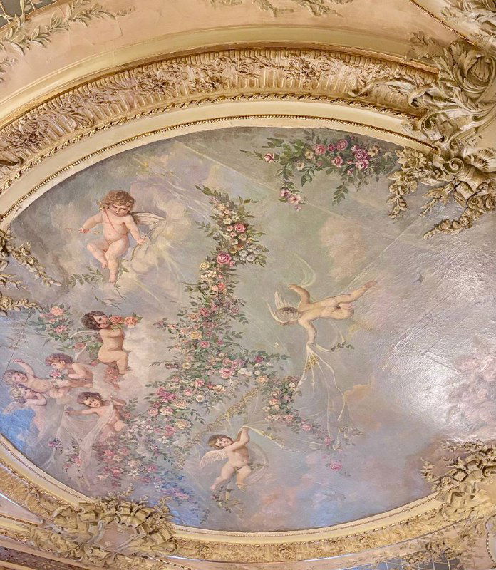 Роспись потолка в зале ресторана Savoy с купидонами, растительными гирляндами и позолоченной лепниной — вид на декор от посетителя.