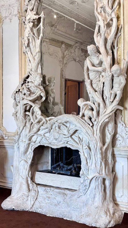 Скульптурный камин с сложной орнаментальной резьбой и витиеватой декоративной композицией в интерьере московской усадьбы