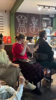 Участники мастер‑класса по жестовому языку сидят у стойки в кофейне, слушают и выполняют задания, видна атмосфера мероприятия.