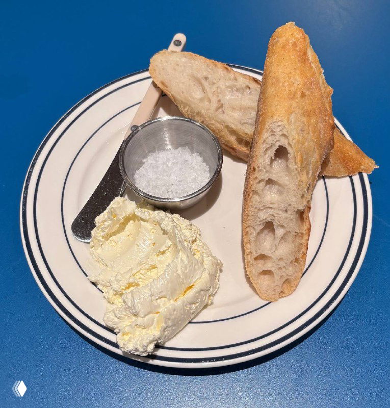 Багет и хлеб с маслом и солонкой на белой тарелке — простая и аппетитная подача хлебной нарезки в Zoe.