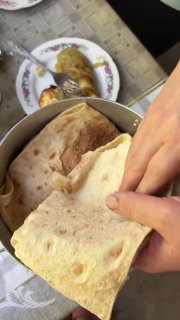 Лаваш, которым оборачивают свежеприготовленный шашлык, крупным планом: тонкий хлеб готовят, чтобы сохранить сочность мяса после снятия с огня.