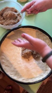 Выкладывание ореховой пасты ложкой на тонкий слой теста, равномерное распределение начинки в форме перед закрытием.