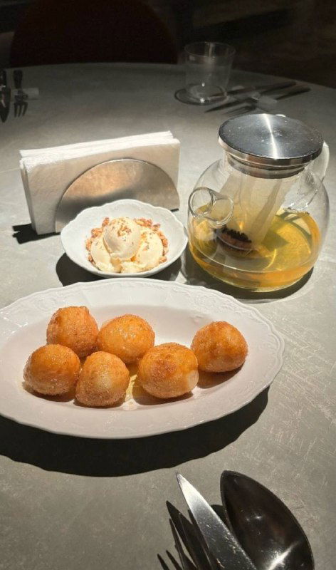 Медовые пышки с мороженым и грецким орехом на белой тарелке, рядом прозрачный чайник и сервировка в ресторане Soma